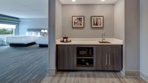 A modern hotel room with a large bed, a kitchenette with a microwave, and a view of the outdoors. - Hampton Inn & Suites by Hilton Burlington Toronto (Burlington)