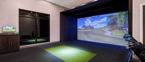A room with a large screen displaying a landscape, a projector, and a tripod with a camera.