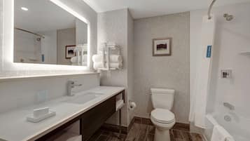 Een moderne badkamer met een grote spiegel, een witte wastafel en een douchehoek.