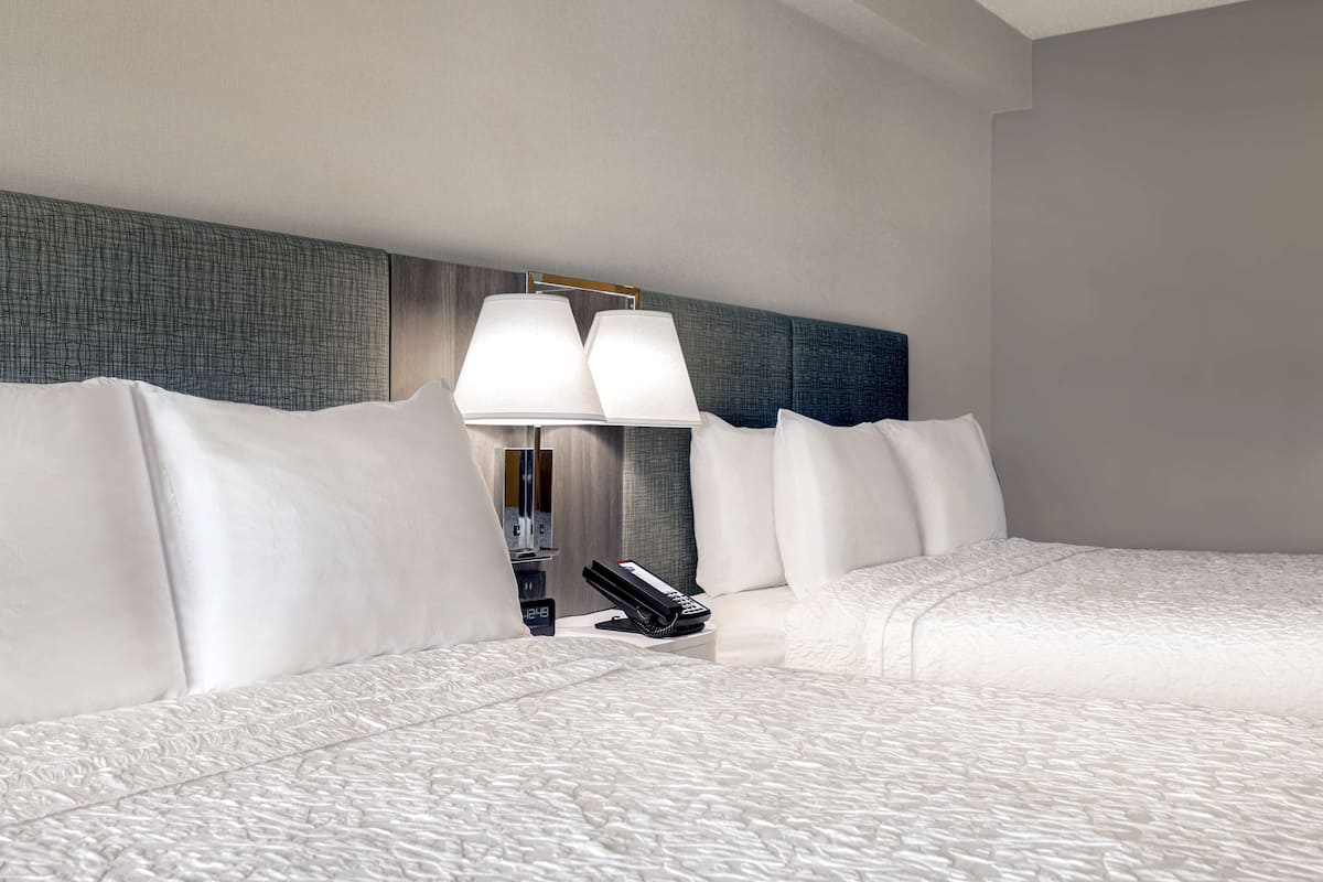 A hotel room with a large bed, a bedside table with a lamp, and a telephone.
