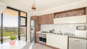 Eine moderne Küche mit Edelstahl-Kühlschrank, -herd und -geschirrspüler, Holzschränken und einer weißen Küchenwand.