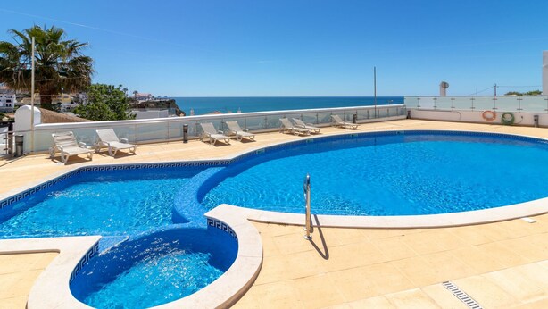 A swimming pool with lounge chairs and a view of the sea. - The Nest - Stunning sea views, communal pool & walking distance to beach (Carvoeiro)