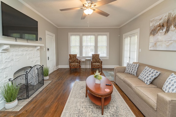 A living room with a fireplace, sofa, coffee table, and a TV mounted on the wall.