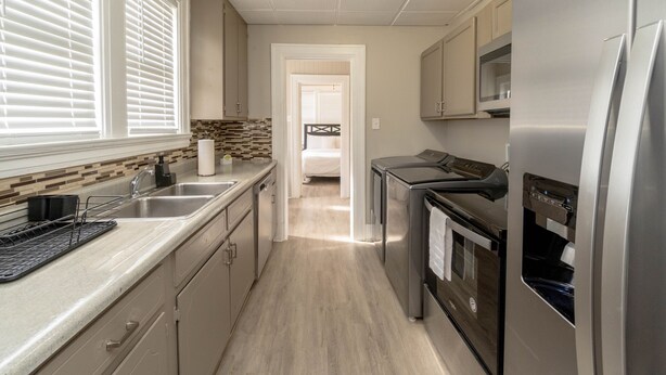 A modern kitchen with stainless steel appliances, a wooden countertop, and a view into the adjacent bedroom. - Cloverdale Large Group Duplex • 6BR • Sleeps 14 (Montgomery)