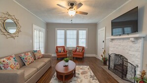 A living room with a sofa, two armchairs, a coffee table, a fireplace, and a television mounted above it. - Cloverdale Large Group Duplex • 6BR • Sleeps 14 (Montgomery)