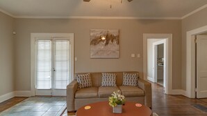 A living room with a beige sofa, a wooden coffee table, and a painting on the wall. - Cloverdale Large Group Duplex • 6BR • Sleeps 14 (Montgomery)