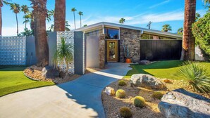 A modern house with a stone facade, a well-maintained lawn, and cacti.