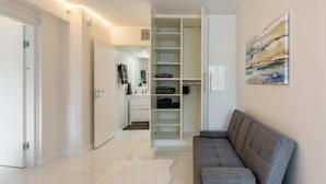 Ein modernes Wohnzimmer mit einem grauen Sofa, einem weißen Teppich und einem begehbaren Kleiderschrank mit Regalen.