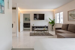 Una sala de estar moderna con un sofá, una mesa de centro, un televisor montado en la pared y una planta en maceta.