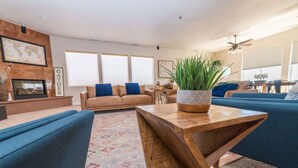 A modern living room with a sofa set, a wooden coffee table, and a large potted plant. - Sleeps 30! Kanab Retreat | Hot Tub & Theater (Kanab)