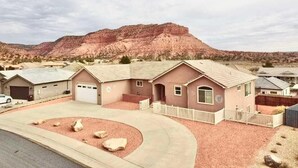 A residential area with houses, a driveway, and a large mountain in the background. - Sleeps 30! Kanab Retreat | Hot Tub & Theater (Kanab)