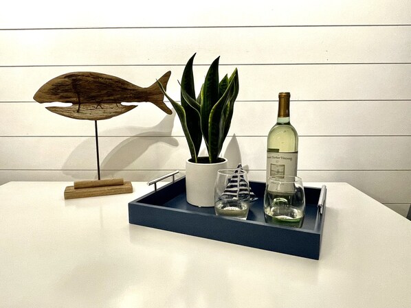 A tray with a potted plant, a bottle of wine, and two glasses on a white table against a white wall. - PONTOON BOAT NOW INCLUDED! KAYAKS! Waterfront Cottage on Mona Lake with HOT TUB! (Norton Shores)
