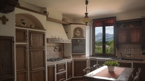 Eine Küche mit Holzausstattung, einem Gasherd und Blick auf Berge durch das Fenster.