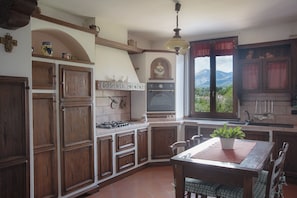 A kitchen with wooden cabinets, a stove, and a dining area with a table and chairs.