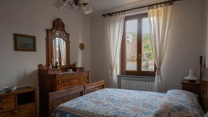 Ein Schlafzimmer mit einem Bett, einer hölzernen Kommode und einem Fenster mit Vorhängen.