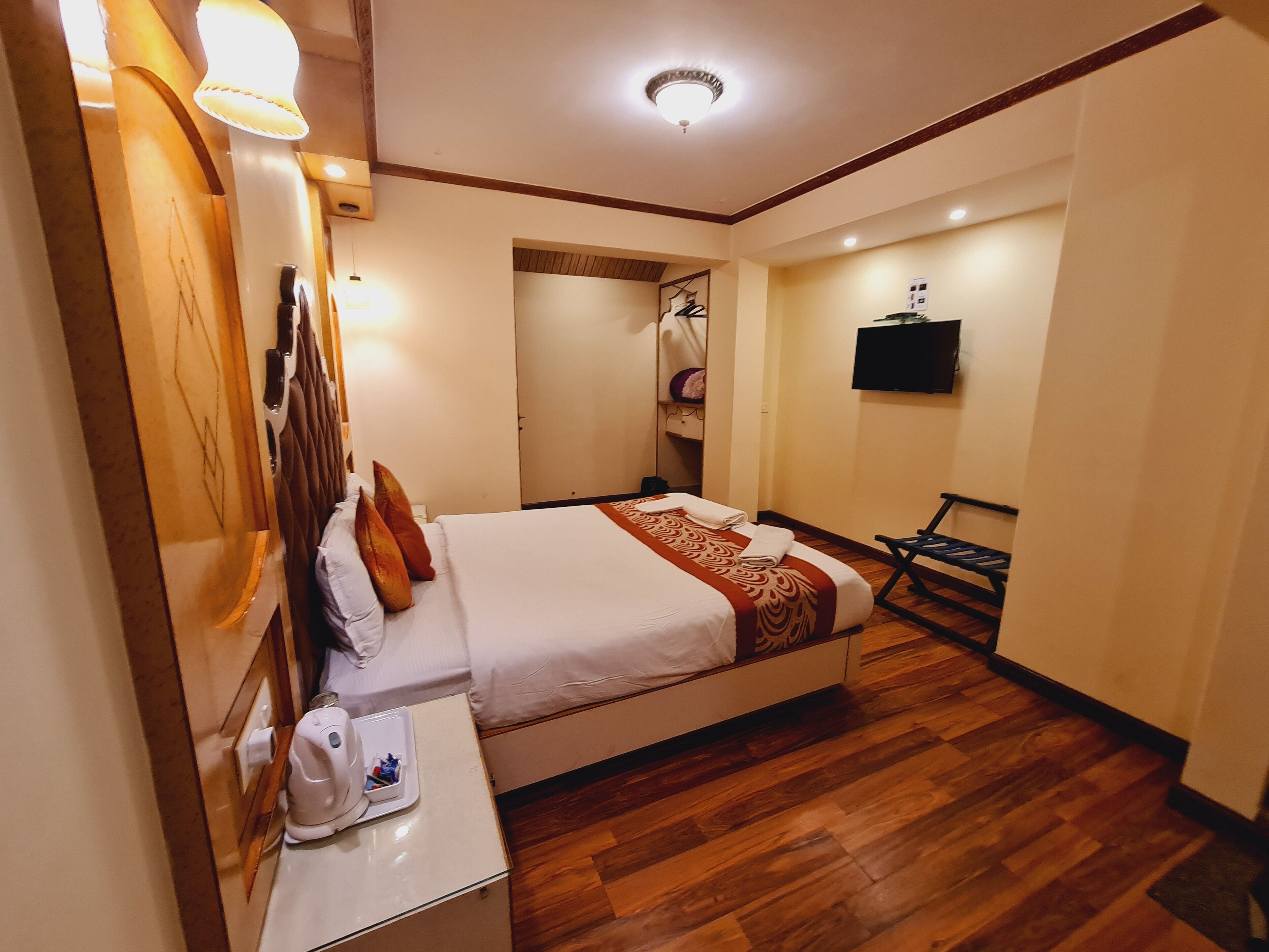 A hotel room with a bed, bedside table, and a TV mounted on the wall.