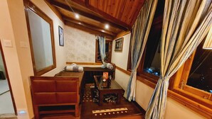 Um quarto aconchegante com um banco de madeira, uma mesa pequena com um vaso e uma janela com cortinas.