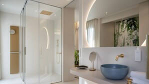 Et moderne badeværelse med en glasbrusekabine, en stor blå skål-vask og et minimalistisk design.
