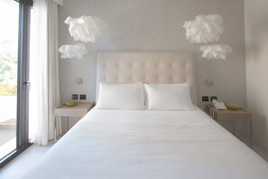 A modern hotel room with a large bed, two bedside tables, a telephone, and a window with curtains.