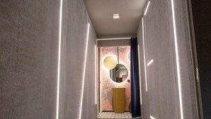 A hallway with a modern design, featuring a tiled floor and walls with vertical light strips. - In A Light Wave: Il mare, l’acqua. Flexibility and inclusiveness (Rimini)