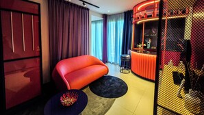 Una sala de estar moderna con un sofá rojo, una mesita redonda y una zona de bar con un letrero de neón.
