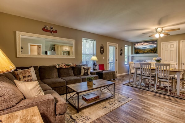 A living room with a sofa, coffee table, and a dining area with chairs and a table.