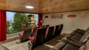 Una sala de cine con un oso como mascota, cortinas rojas y techo de madera.