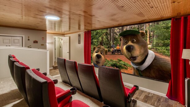 Una habitación con un ventanal grande, techo de madera y vistas a un bosque.