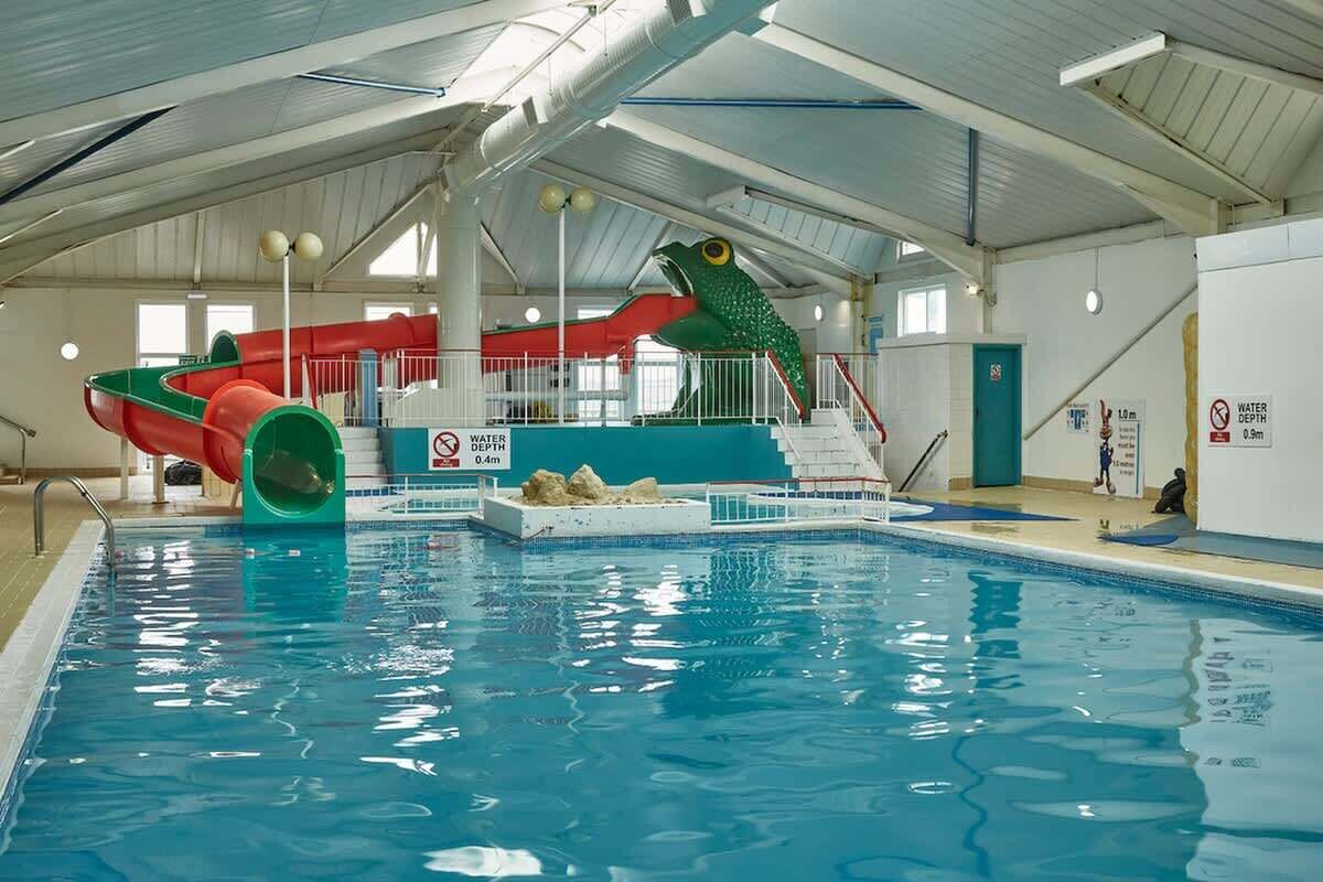 Ein Hallenbad mit Wasserrutsche, Sprungbrett und einer hasen-förmigen Wasserspende.