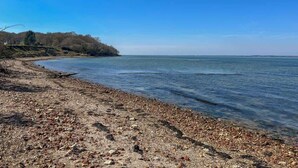 Uma praia de pedras com vista clara para o mar e terra ao longe.