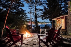 Une terrasse en pierre avec des fauteuils Adirondack et un foyer, offrant une vue imprenable sur la côte.