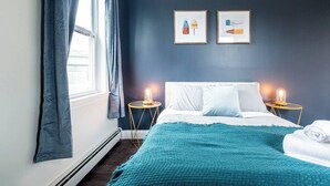 A bedroom with a bed, two bedside lamps, a window with curtains, and two framed pictures on the wall. - ★ Modern Renovation ★ 10-Bedrooms! Perfect For Large Groups! (Providence)