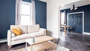 A living room with a sofa, coffee table, and a dining area with a table and chairs. - ★ Modern Renovation ★ 10-Bedrooms! Perfect For Large Groups! (Providence)