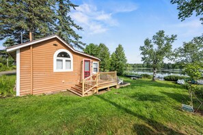A wooden cabin with a porch and a view of a lake.