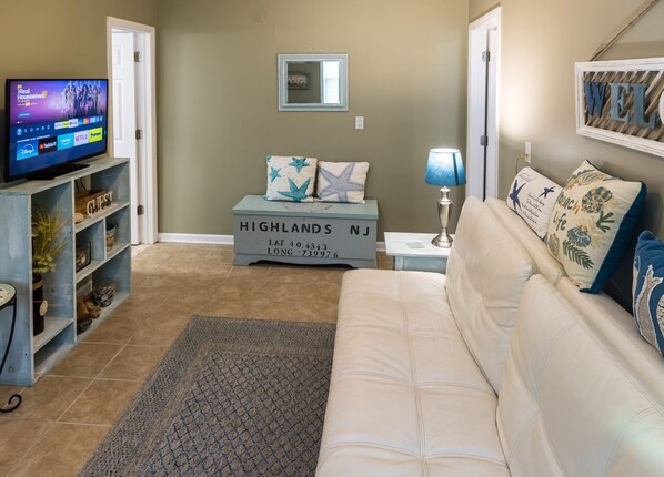 A living room with a television, a sofa, a coffee table, and a rug.