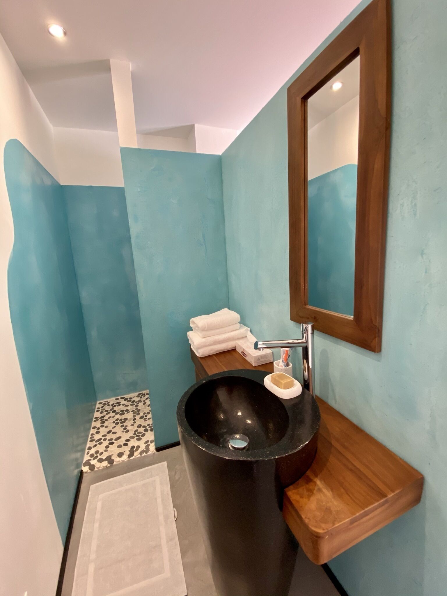 A bathroom with a black sink, a wooden vanity, a mirror, and a tiled floor.