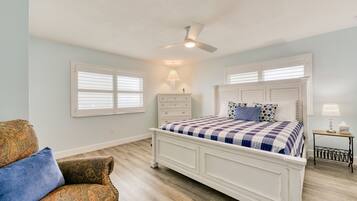 A bedroom with a bed, a chair, a nightstand, and a ceiling fan.