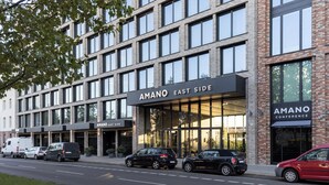 A modern building with "AMANO EAST SIDE" signage, featuring a glass facade and multiple parking spaces. - Hotel AMANO East Side (Berlin)