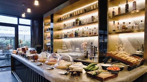 A bar area with a marble countertop, various bottles, glasses, and food items. - Hotel AMANO East Side (Berlin)