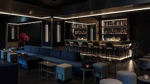 A modern bar area with a sofa, seating, and a bar counter. - Hotel AMANO East Side (Berlin)