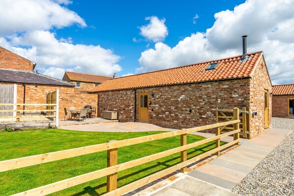 A brick building with a tiled roof, a wooden fence, and a grassy lawn. - Brecks Farm - The Parlour - a family break that sleeps 4 guests in 1 bedroom (York)
