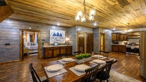A rustic cabin interior with a dining area, kitchen, and a cozy bedroom. - Blue Pine Divine - 1+ Bedrooms, 2 Baths, Sleeps 6, pet friendly, Hot Tub (Broken Bow)