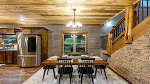 A dining area with a wooden table, chairs, and a chandelier. - Blue Pine Divine - 1+ Bedrooms, 2 Baths, Sleeps 6, pet friendly, Hot Tub (Broken Bow)