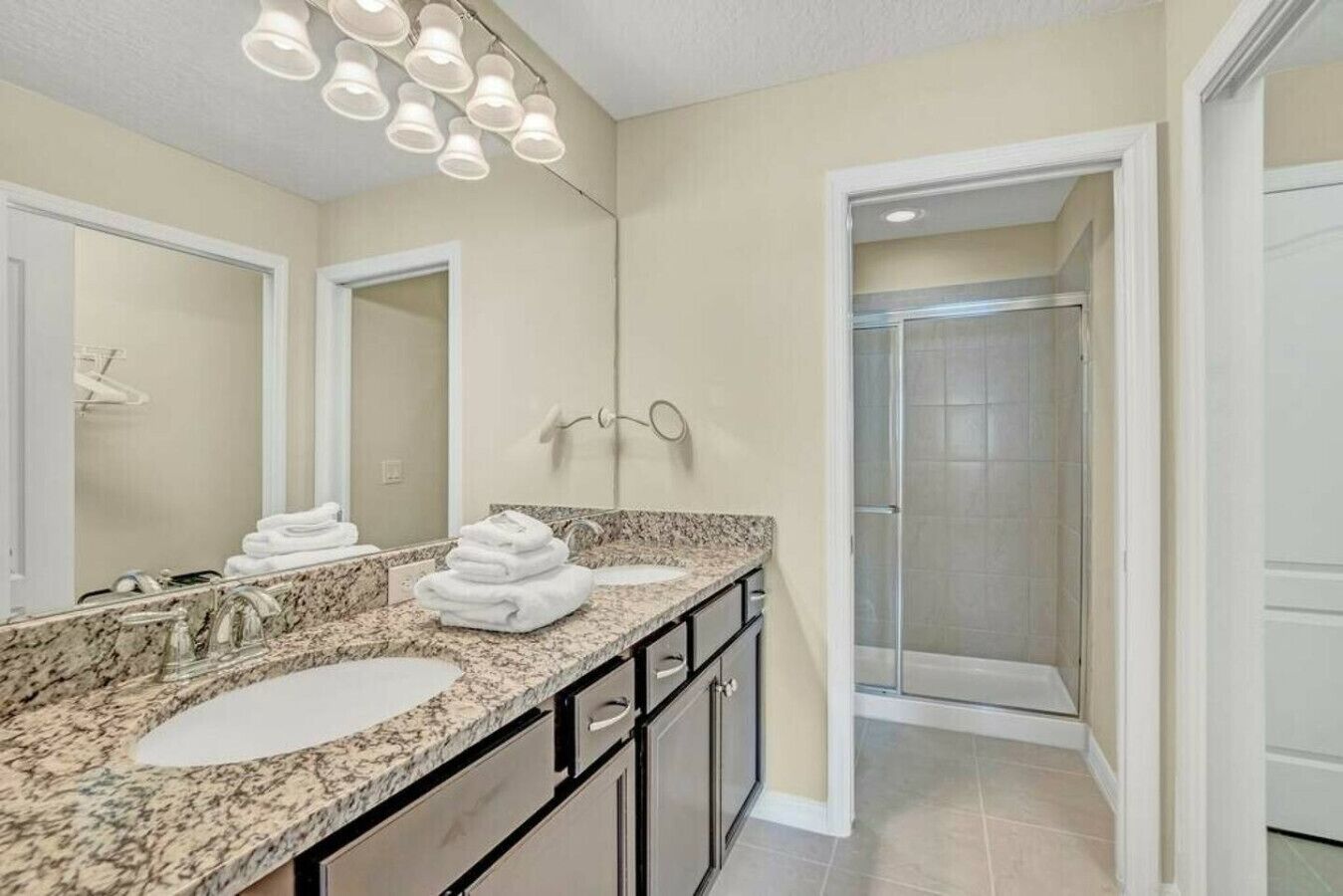 A bathroom with a large mirror, two sinks, and a shower area.