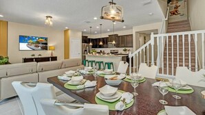 A dining area with a wooden table set for six, surrounded by white chairs. - Themed rooms - Resort acess (Kissimmee)