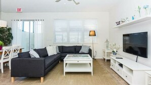 A modern living room with a sectional sofa, a coffee table, a TV, and a ceiling fan. - Great Lake View - Pet Friendly (Kissimmee)