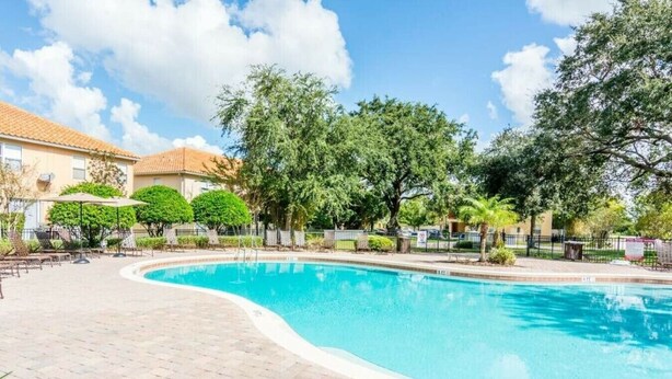 A swimming pool with a brick patio, surrounded by trees and a fence. - Great Lake View - Pet Friendly (Kissimmee)