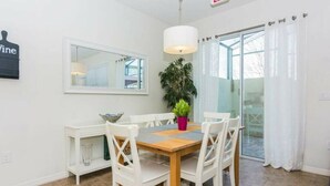 A dining area with a wooden table, white chairs, a potted plant, and a large mirror on the wall. - Great Lake View - Pet Friendly (Kissimmee)