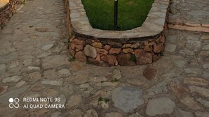 Uma trilha de pedra que leva a uma casa com muro de pedra e um pequeno gramado.