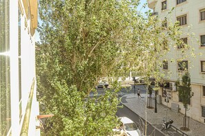 A street view with a tree, buildings, and a parked car.